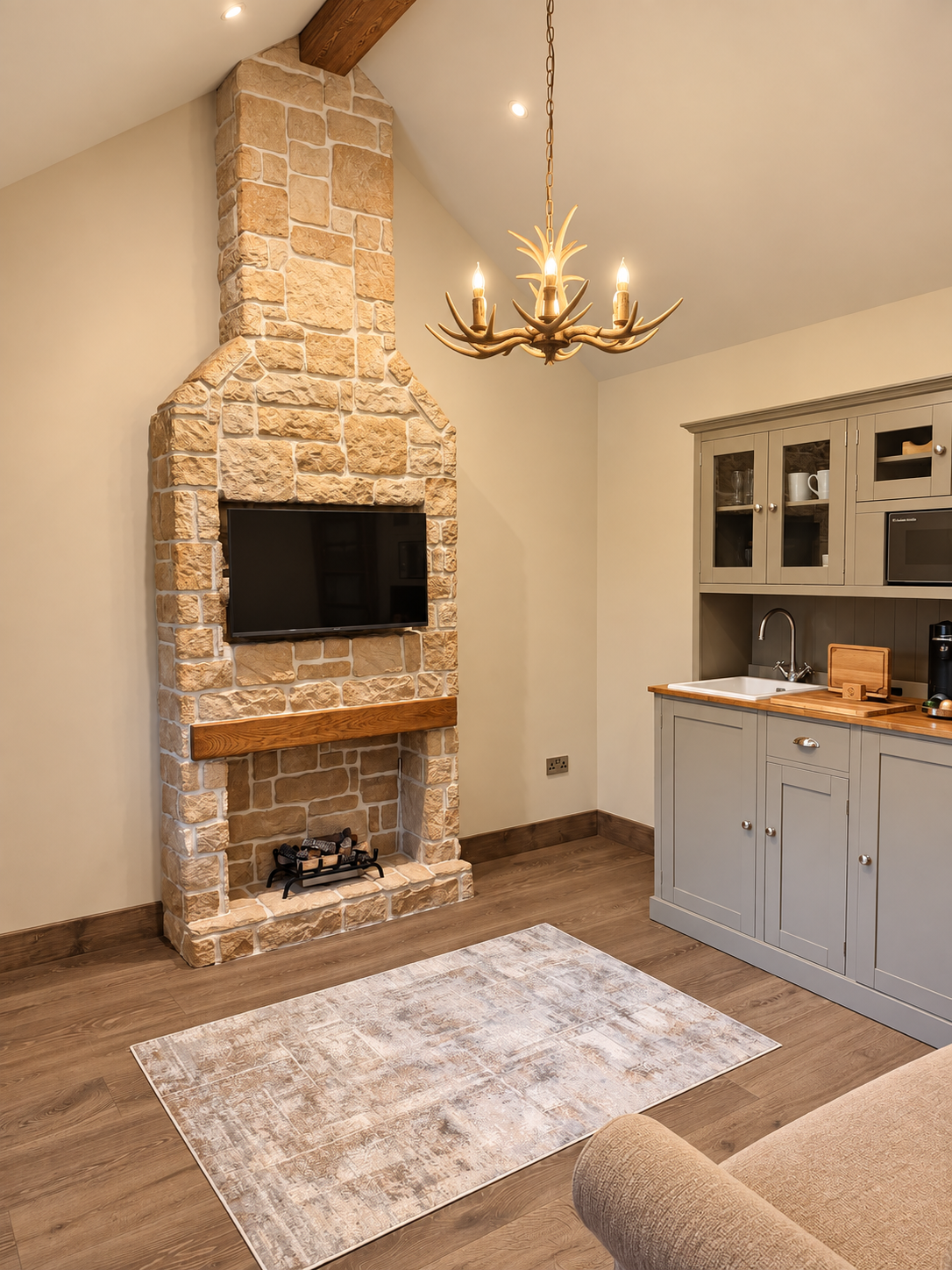 Living area with stone fireplace and grey kitchenette